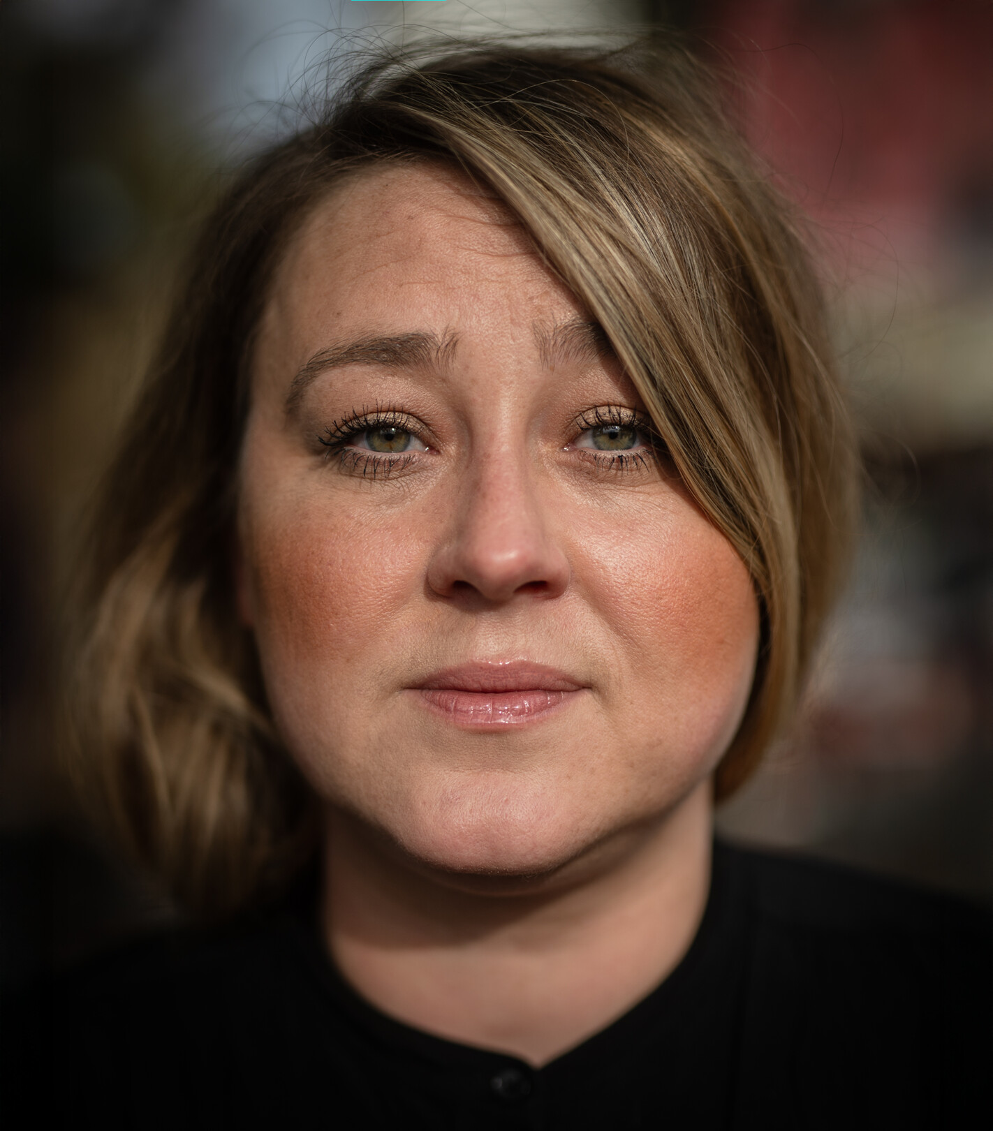 Man sieht eine Frau mit schulterlangen mittelblonden Haaren, die in die Kamera guckt.