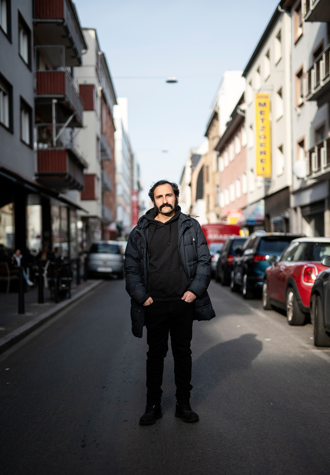 Amir Gudarzi steht auf einer Straße und blickt in die Kamera.