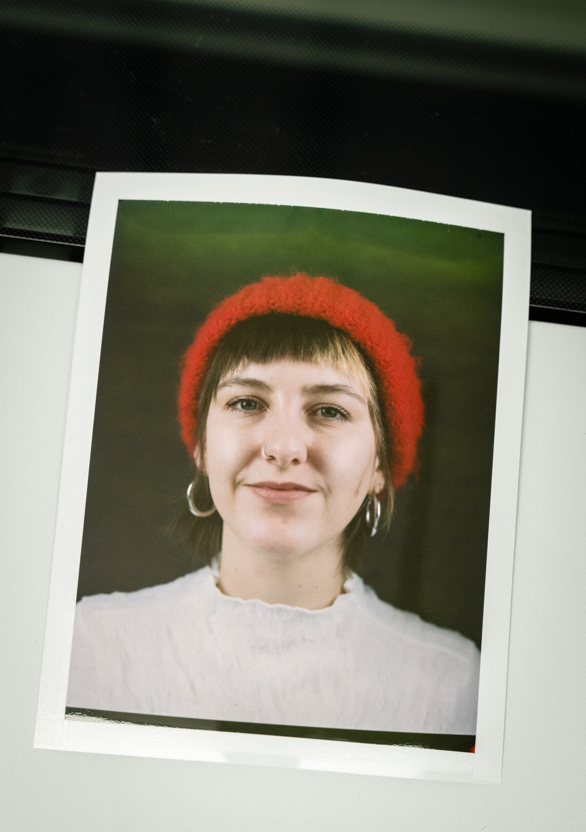 Auf dem Bild ist eine Frau mit braunen kurzen Haaren zu sehen, die eine rote Mütze trägt und lächelnd in die Kamera schaut.