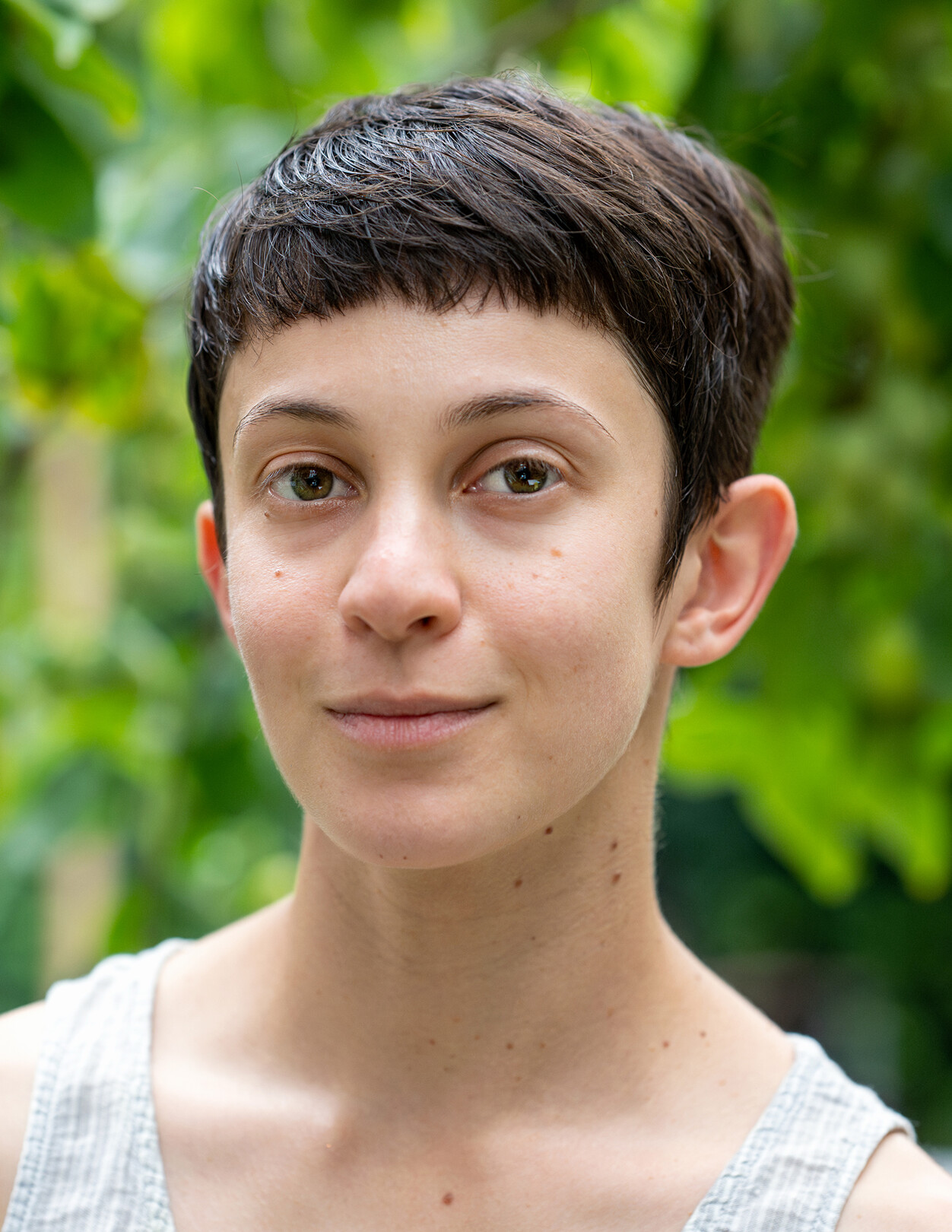 Man sieht eine junge Frau mit kurzen braunen Haaren, die in die Kamera schaut.